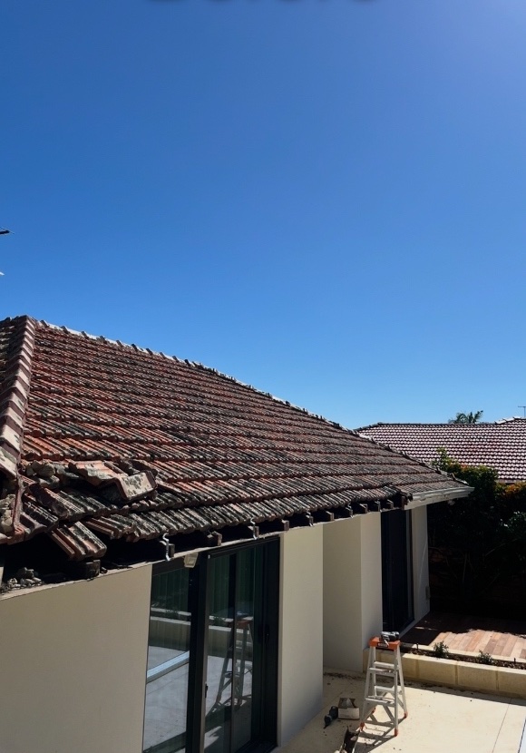 Before: Tiled roof with broken, slipping tiles along the gutter edge