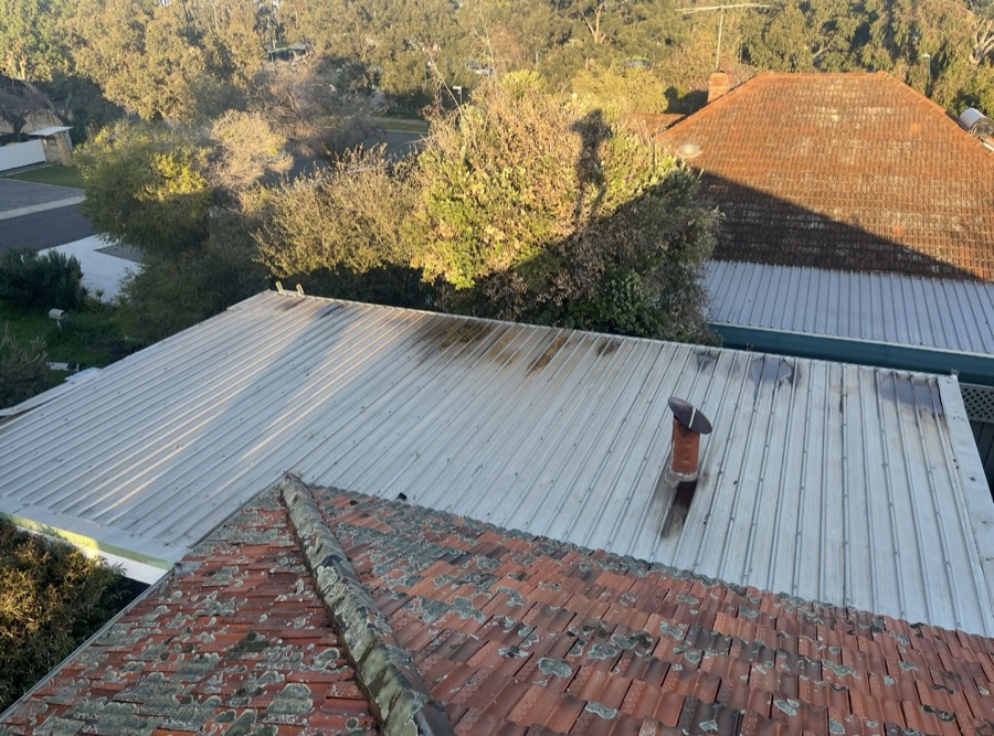 Before: Old, stained metal roof sheets beside a tiled roof
