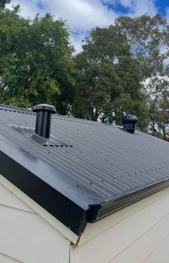 After: The finished black metal roof with vents and gutter