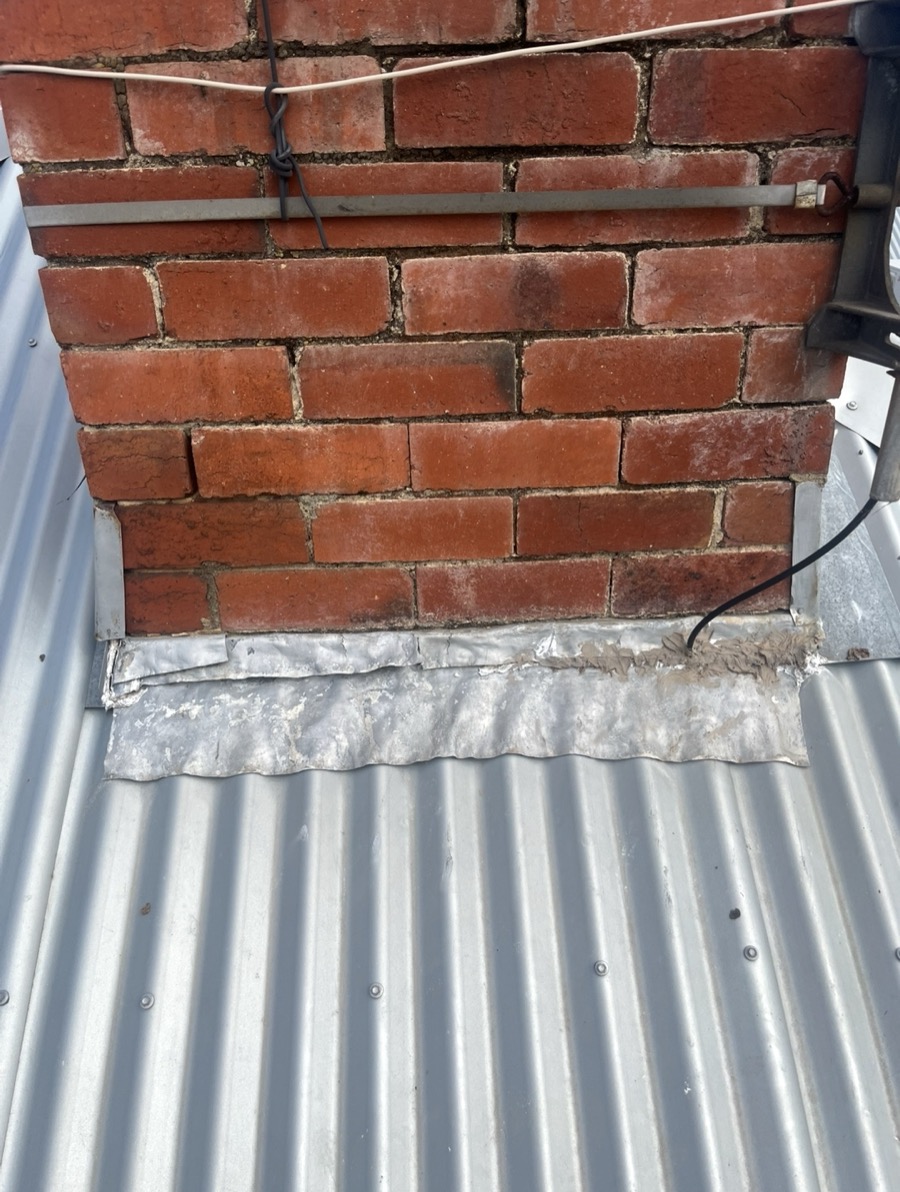 Before: Old, patched lead flashing at the base of a brick chimney
