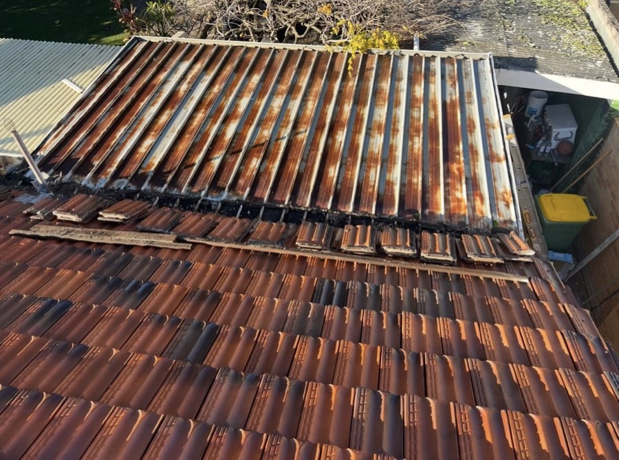 Before: Rusted, corroded roof sheets above a tiled roof