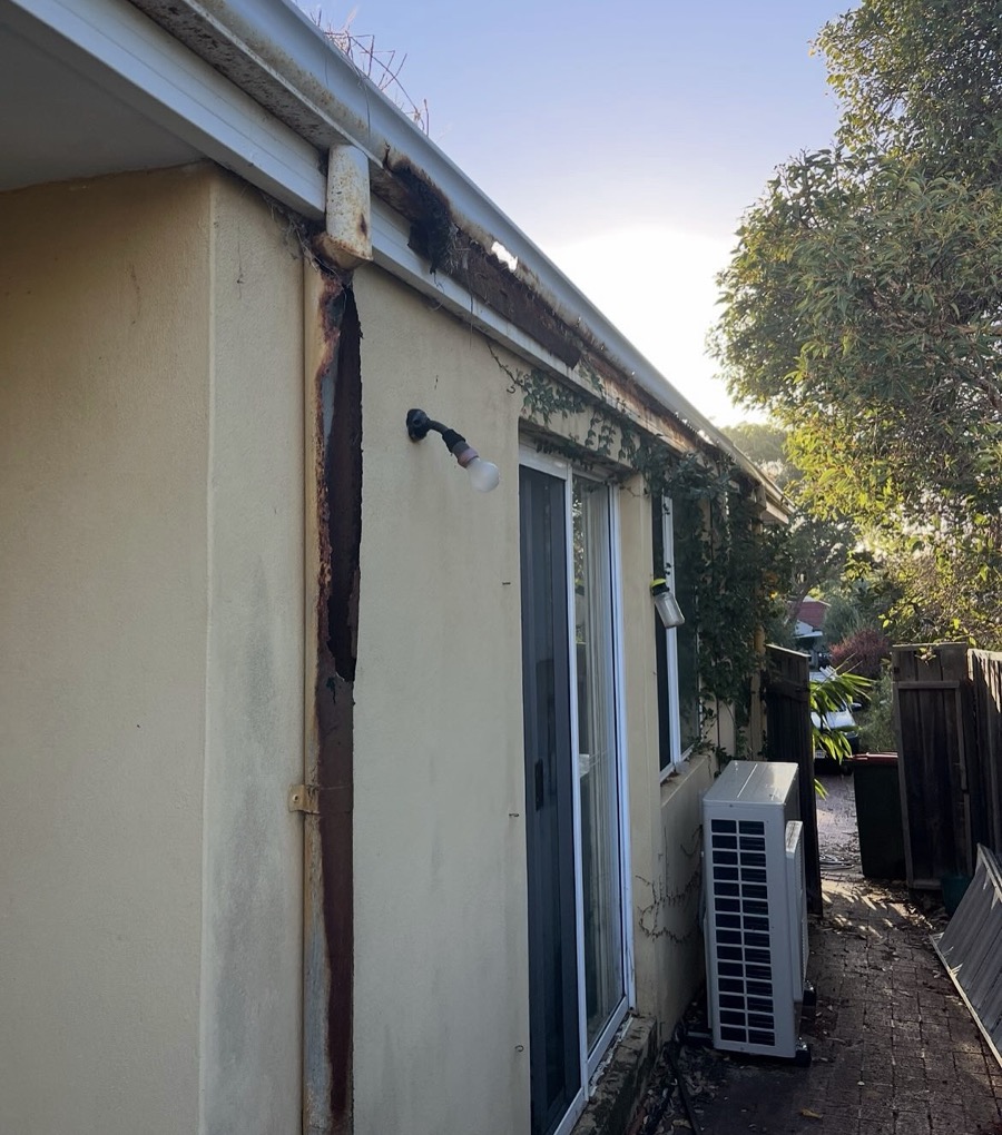 Before: Rusted gutter and a split, rust-stained downpipe down the wall