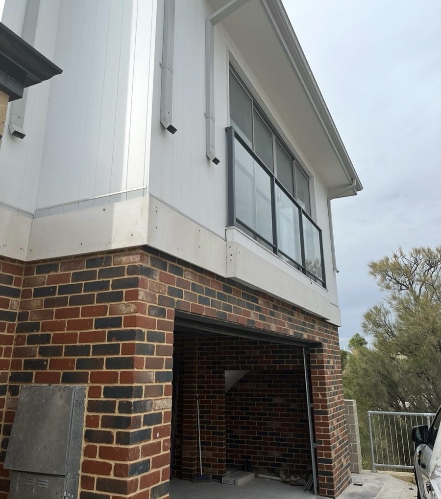 Before: Two-storey home with unfinished cladding and no lower downpipes