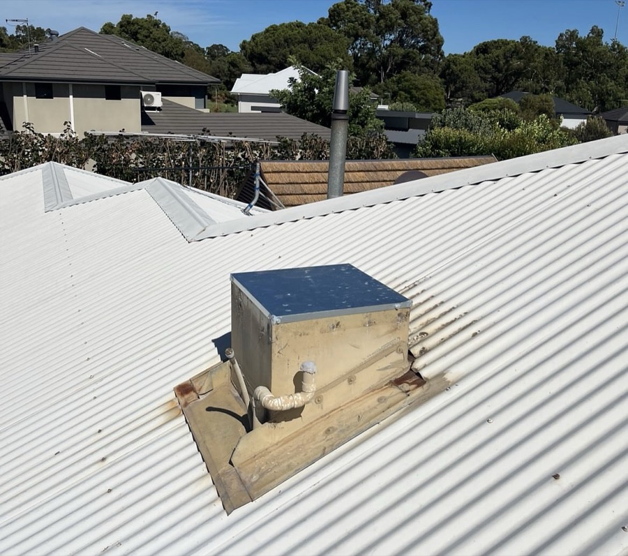 Before: Rust-stained roof sheets around a rooftop unit
