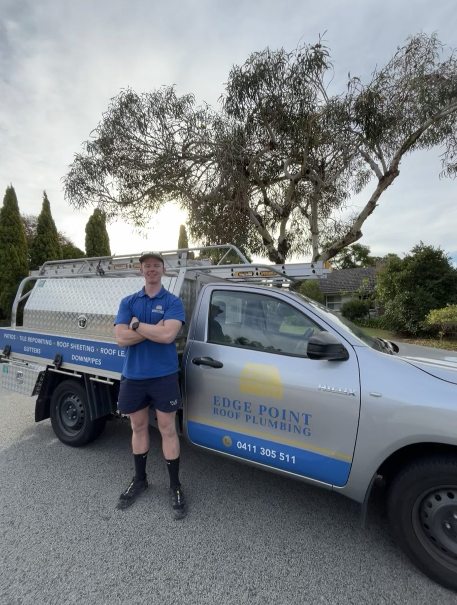 Ryan, owner of Edge Point Roof Plumbing, standing beside the signwritten Edge Point ute