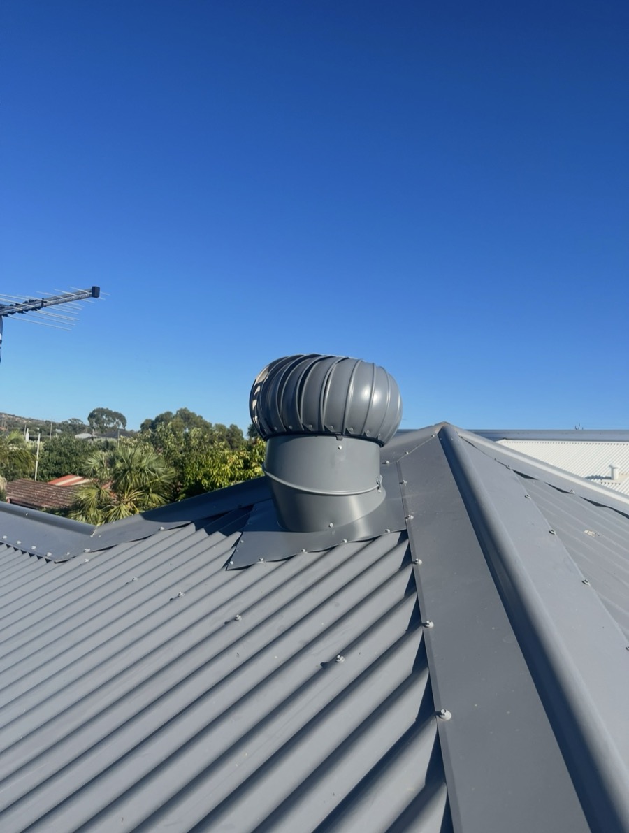 A whirlybird installed by Edge Point Roof Plumbing, flashed into a grey metal roof